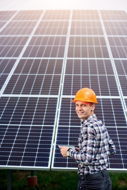 Station de batterie solaire et travailleur dans un casque et avec une tablette dans les mains à proximité