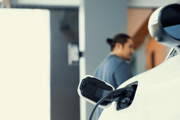 Station de charge Focus EV à la maison avec un homme progressif flou en arrière-plan