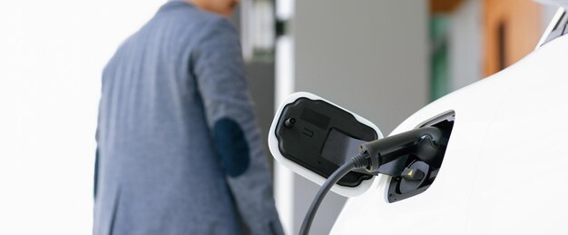 Station de charge Focus EV à la maison avec un homme progressif flou en arrière-plan