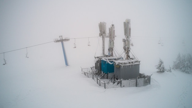 La station mobile couverte de neige et de glace lance des funiculaires dans un pays d'hiver rigoureux dans le brouillard. Concept touristique dans les endroits difficiles et les pays du nord