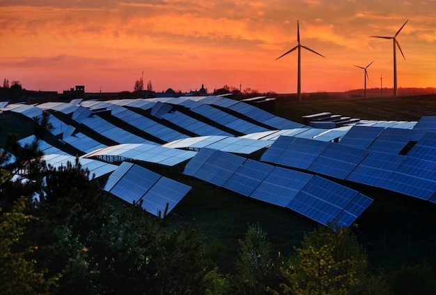 Station de panneaux solaires et équipement de générateur d'énergie éolienne au coucher du soleil concept d'énergie alternative ciel rouge