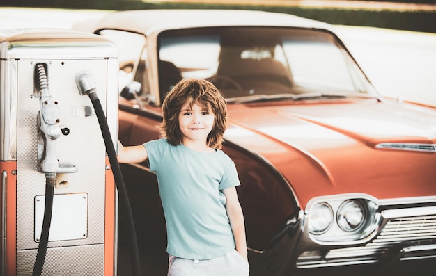 Station-service rétro Smiling Kid garçon à la station-service En attente de carburant Enfant faisant le plein d'une voiture vintage à la station-service Faire le plein d'essence