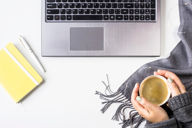 Station de travail automne avec ordinateur portable, planeur, stylo et tasse à café avec des mains féminines