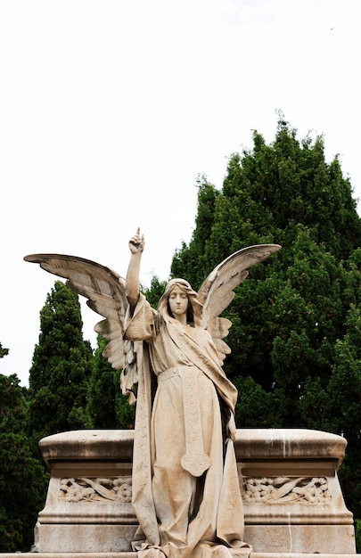 Une statue d'ange avec la main droite pointant vers le haut.