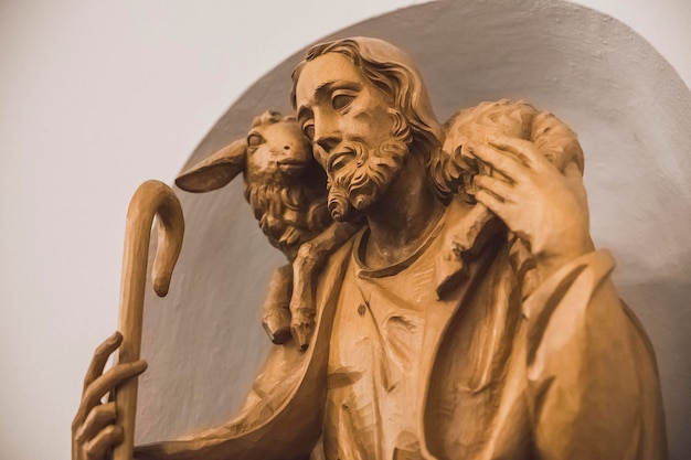 Statue en bois sculpté de Jésus avec un agneau sur ses épaules dans l'église