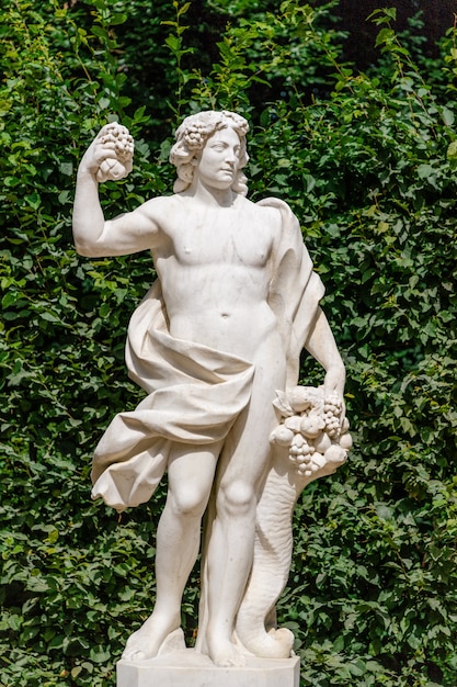 Statue avec corne d'abondance sur fond de feuilles vertes au palais de Sanssouci. Potsdam, Allemagne
