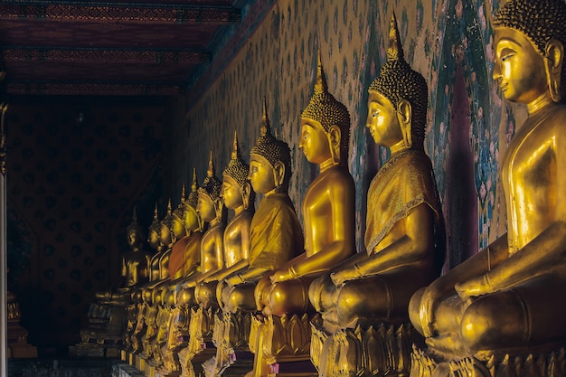 Statue dorée de Bouddha sur le piédestal avec de vieux murs