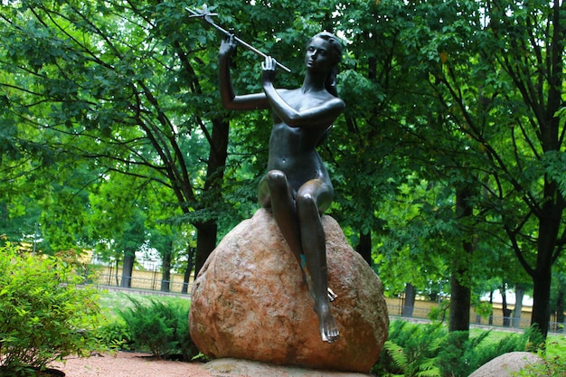 Une statue d'une femme assise sur un rocher avec une flûte dessus.