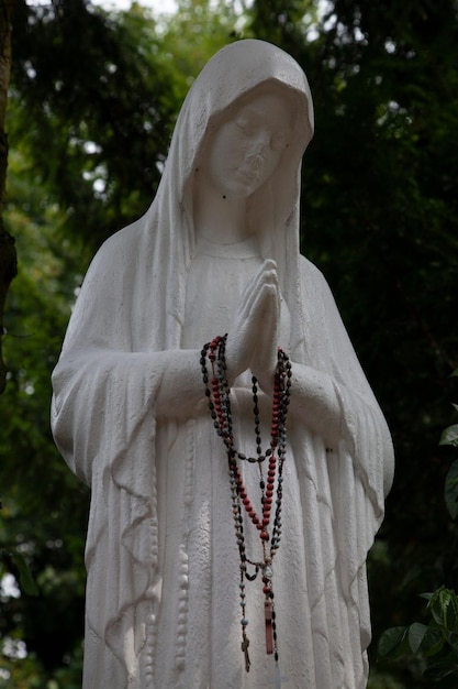 Statue d'une femme dans un cimetière en deuil et en prière avec des perles de prière sur ses mains