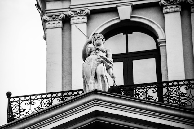 une statue d'une femme est sur un balcon au-dessus d'un bâtiment