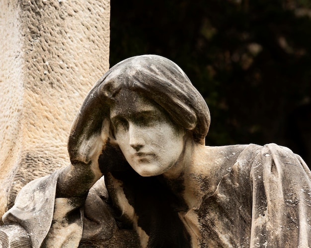 Une statue de femme la tête sur la tête est devant une colonne.