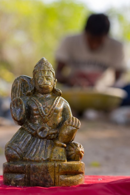 Statue d'Hanuman avec un homme lavant d'autres œuvres d'art en arrière-plan à Chamundi Hills à Mysore