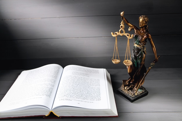 Statue de la justice et livre sur fond gris