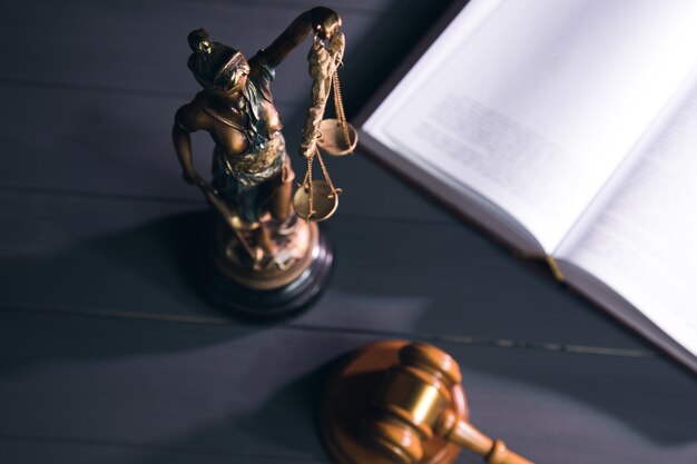 Statue de la justice, livre et marteau sur table en bois