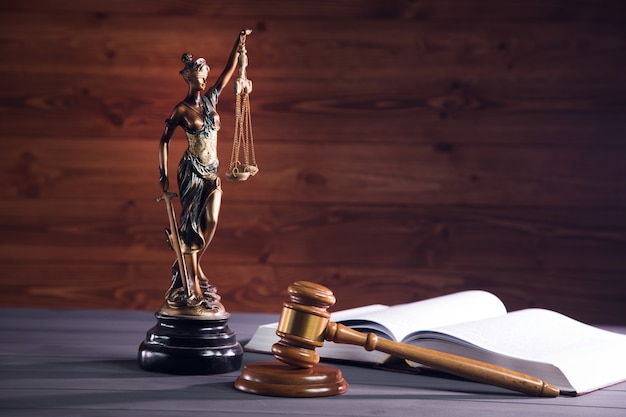 Statue de la justice, livre et marteau sur table en bois