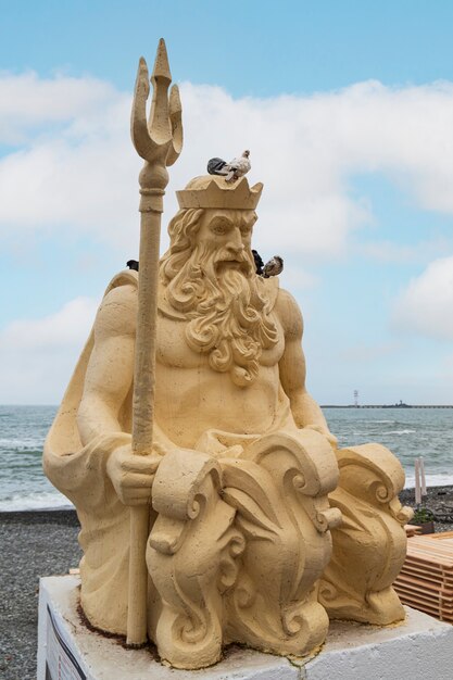 Statue de Neptune avec trident en bord de mer