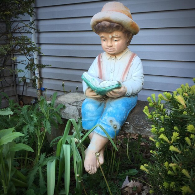 Photo statue par des plantes sur un siège dans la cour