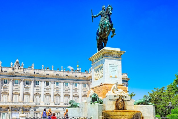 Statue de Reinando Isabel Segunda de Borbon, derrière elle se trouve le Palais Roal avec des gens et des touristes.