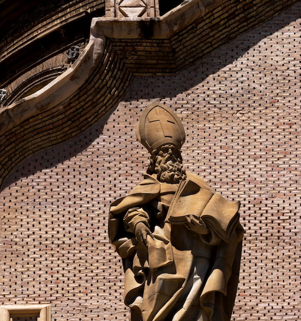 Une statue d'un saint surmontée d'une croix