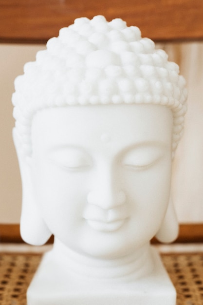 Photo statue de tête de bouddha en céramique blanche sur une chaise en bois