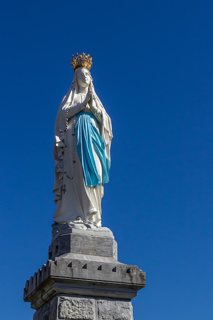 Statue de la Vierge Marie à Lourdes contre le ciel bleu