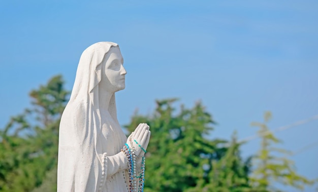 Statue de Vierge Marie priant sous un ciel bleu