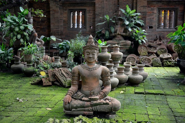 Des statues abandonnées par des vases sur un sol en carreaux recouvert de mousse contre le mur.