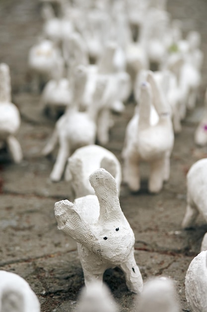 Des statues de lapin blanc en plâtre bouchent une exposition d'art en plein air des lièvres blancs artificiels