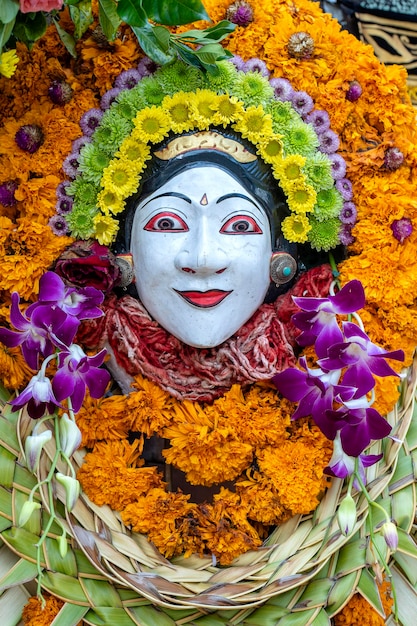 Statuette en pierre traditionnelle balinaise de la divinité décorée de fleurs dans le temple de la rue Island Bali Indonésie Close up