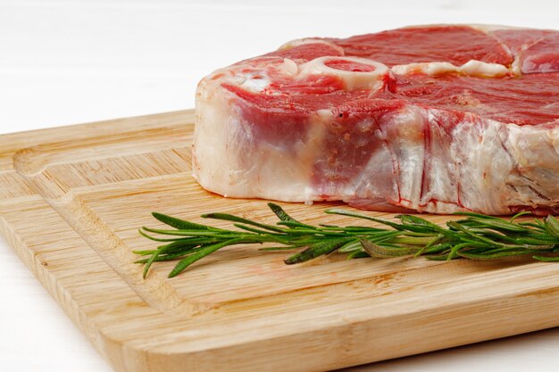 Steak d'agneau cru à bord sur table en bois blanc