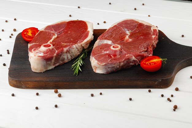 Steak d'agneau cru à bord sur table en bois blanc