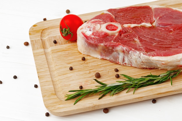 Steak d'agneau cru à bord sur une table en bois blanc