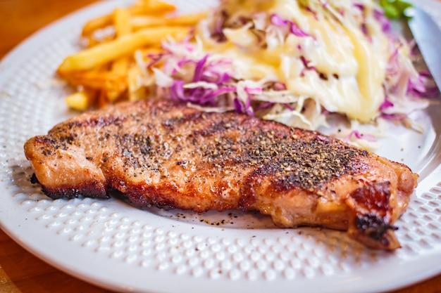 Steak au poivre noir servi avec une salade de légumes.