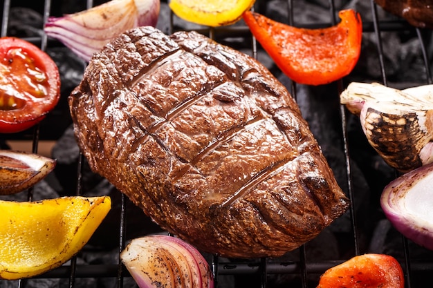 Photo steak de bœuf au jus sur un barbecue avec des légumes