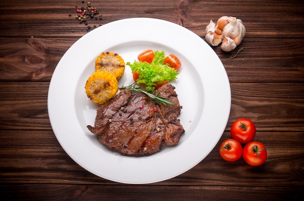 Steak de boeuf aux légumes et assaisonnement sur un fond en bois