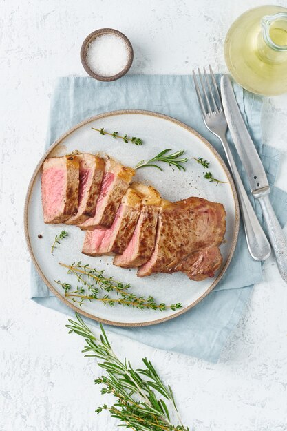 Photo steak de boeuf cétogène régime cétogène, contre-filet sur plaque grise sur blanc.