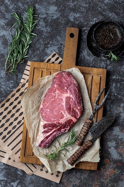 Steak de boeuf cru au romarin sur une table en bois sombre