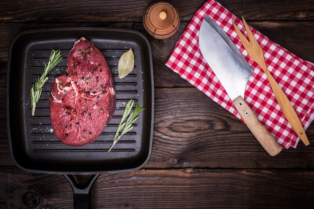 Steak de bœuf cru aux épices sur une poêle noire