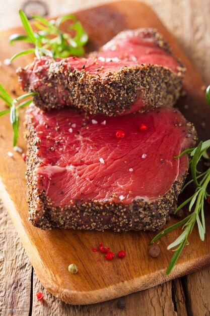 Steak de boeuf cru aux épices et romarin sur fond de bois