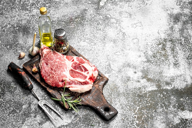 Steak de boeuf cru aux épices et romarin sur table rustique.