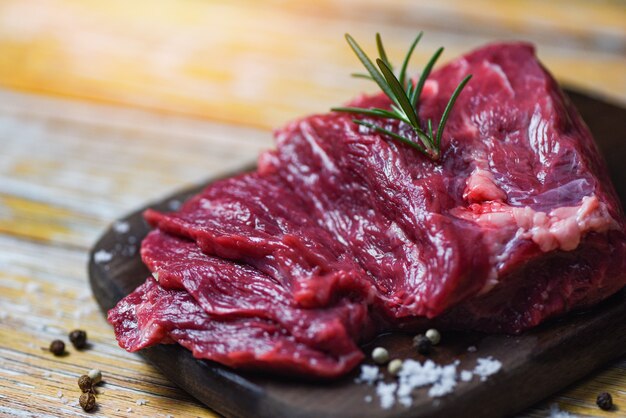 Steak de boeuf cru aux herbes et épices - Viande de bœuf fraîche tranchée sur une planche à découper en bois