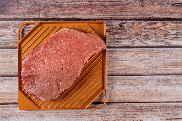 Steak de bœuf cru biologique sur une table en bois.