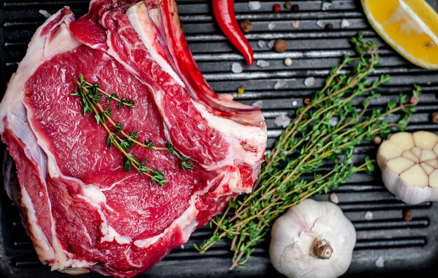 steak de boeuf cru dans une lèchefrite avec des épices sur un fond de bois