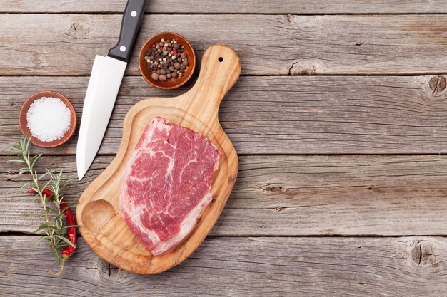 Steak de boeuf cru et épices sur table en bois