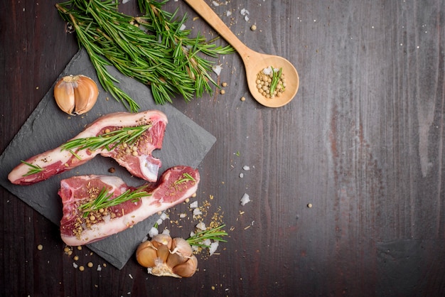 Steak de boeuf cru frais et ingrédients sur planche de pierre noire sur table en bois noir