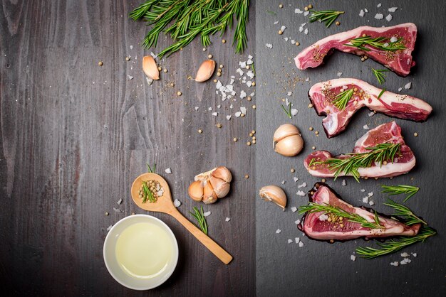 Steak de boeuf cru frais et ingrédients sur planche de pierre noire sur table en bois noir