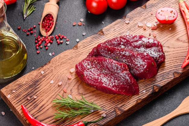 Steak de boeuf cru frais Mignon, avec sel, grains de poivre, thym, tomates. Viande fraîche marbrée crue Steak et assaisonnements