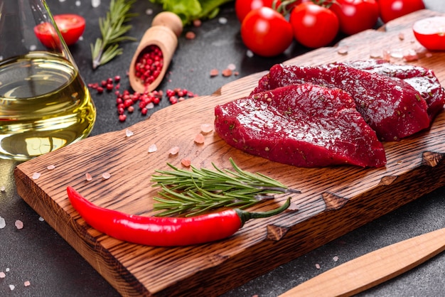 Steak de boeuf cru frais Mignon, avec sel, grains de poivre, thym, tomates. Viande fraîche marbrée crue Steak et assaisonnements