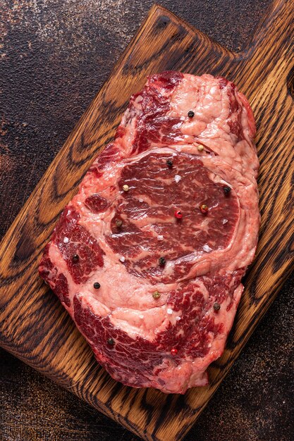 Steak de boeuf cru frais sur une planche à découper en bois