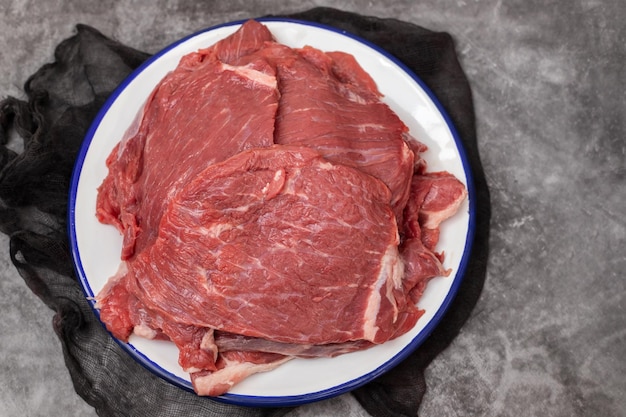Steak de boeuf cru frais sur plat blanc